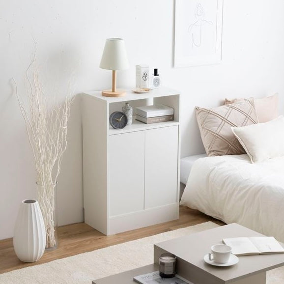 白の扉付きの収納とオープン棚が組み合わさったキャビネットを部屋の中でベッドの横に置いている