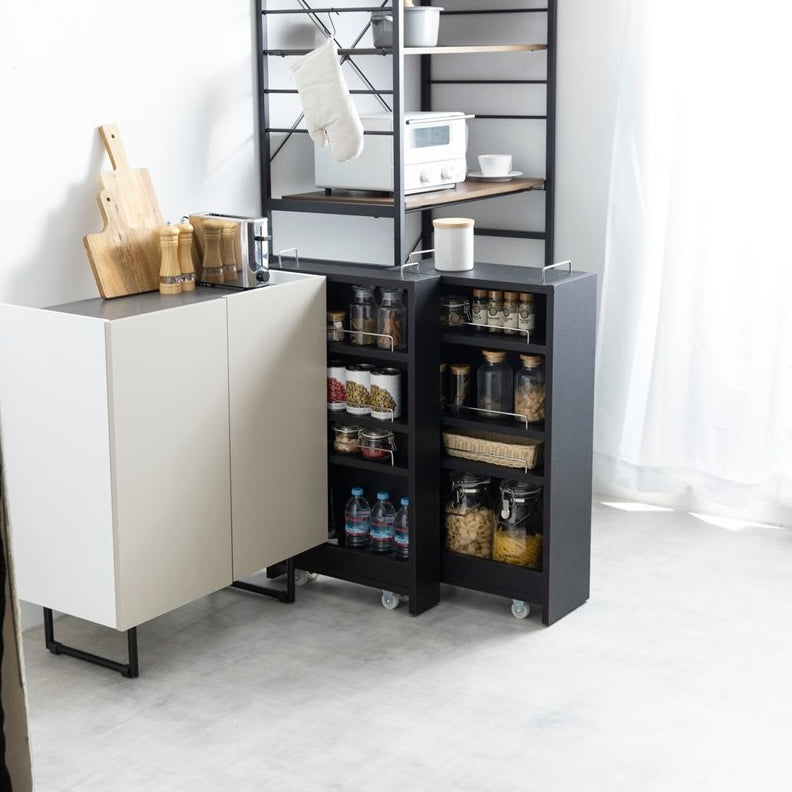 隙間に収まる黒の収納ワゴンをキッチンで使い、食品や水のストックを保管している