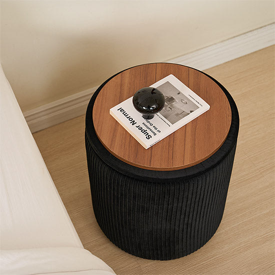 ブラックの楕円型のプリーツ収納がサイドテーブルとしてベッド横に置かれている様子