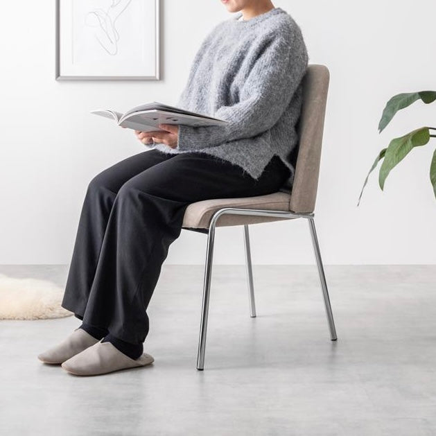 シルバー脚がお洒落なファブリック素材のチェアに人が座っている