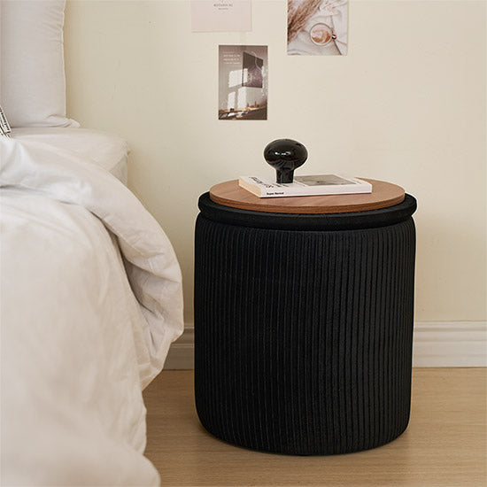 ブラックの楕円型のプリーツ収納がサイドテーブルとしてベッド横に置かれている様子