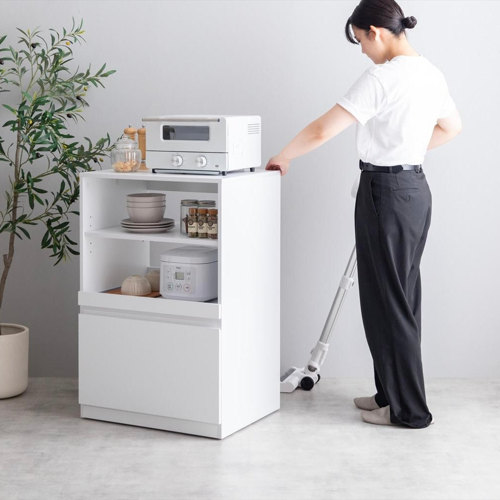 コンパクトなサイズ感のシンプルなキッチンラックの裏を掃除している様子