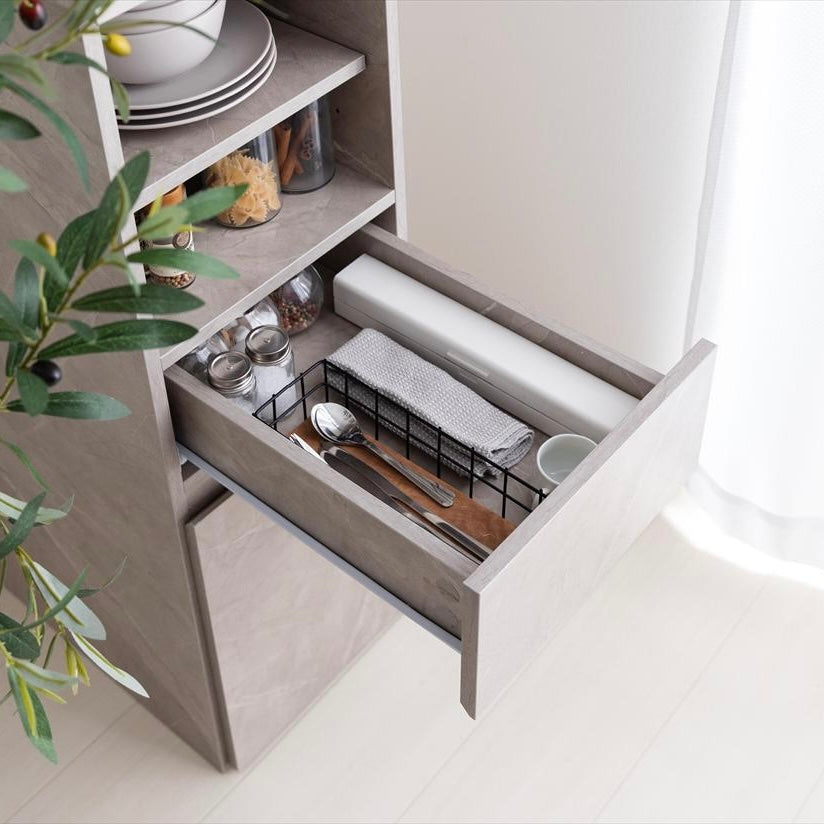 グレーの隙間キッチンボードにカトラリー類が収納されている