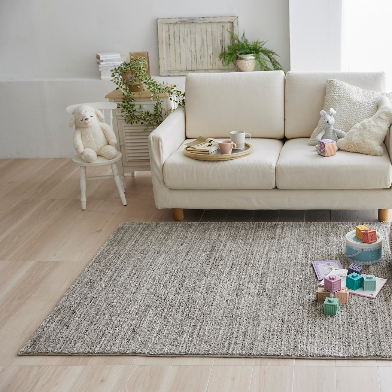 グレージュのナチュラルラグをソファ前に敷いている様子