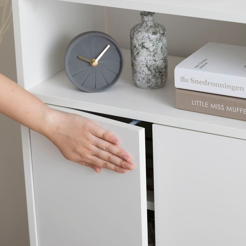 白の扉付きの収納とオープン棚が組み合わさったキャビネットの扉をプッシュオープンしている様子