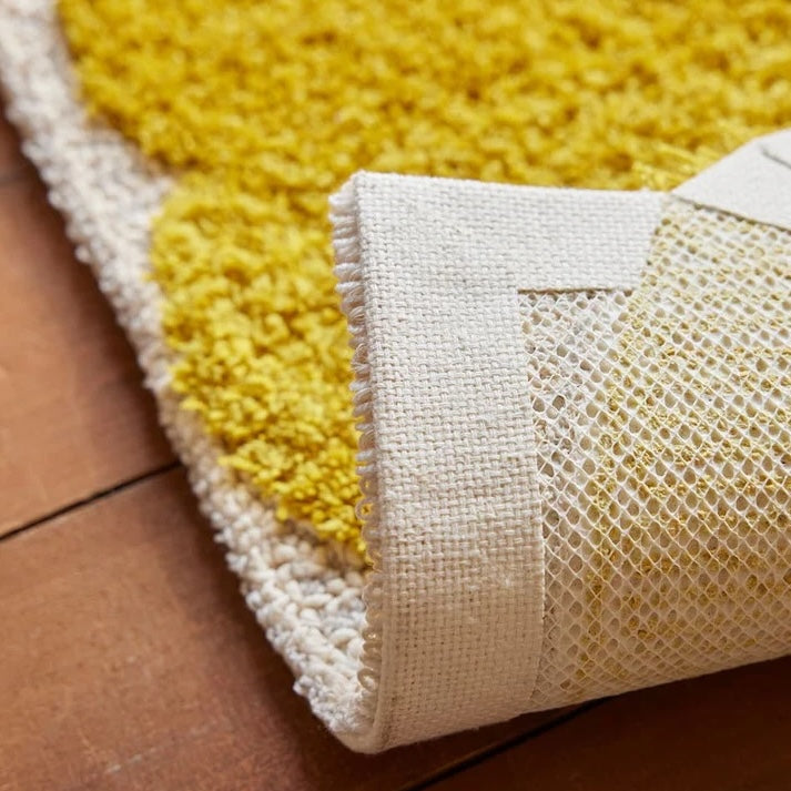 黄色いカラーが目を惹くラグマットの裏面の滑り止めの写真