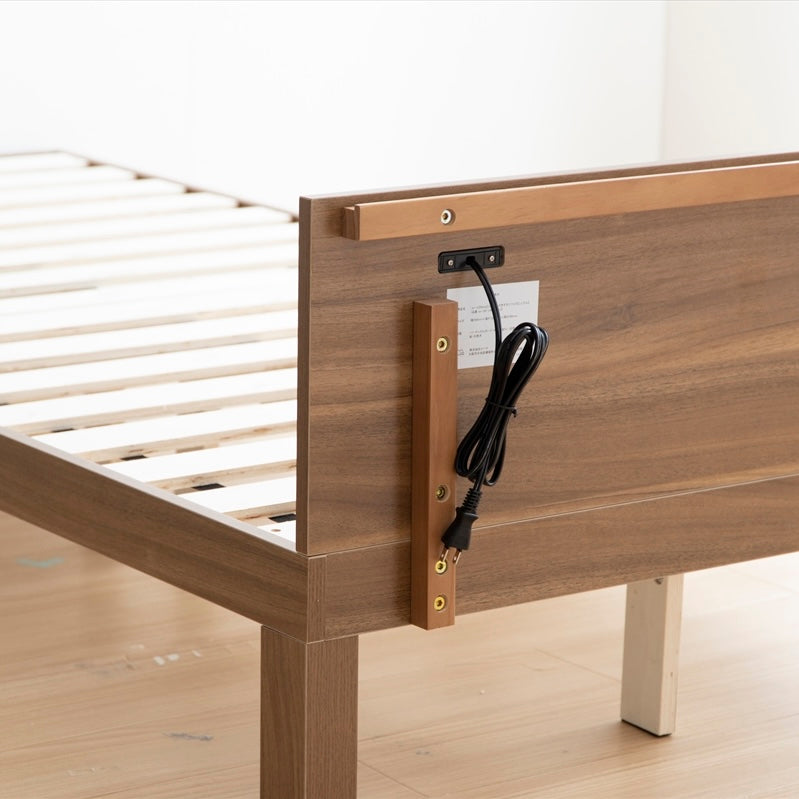 天然木製のブラウンのヘッドボードに2口コンセントが付いたシンプルなベッドフレームのヘッドボード部分のコンセントコードの写真