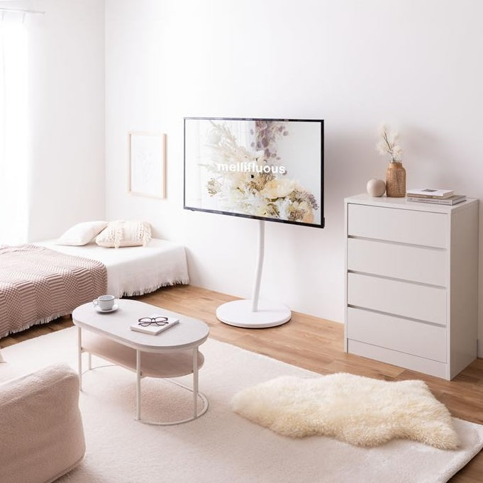 ホワイトのキャスター付きテレビスタンドにテレビを掛けて部屋に置いている様子