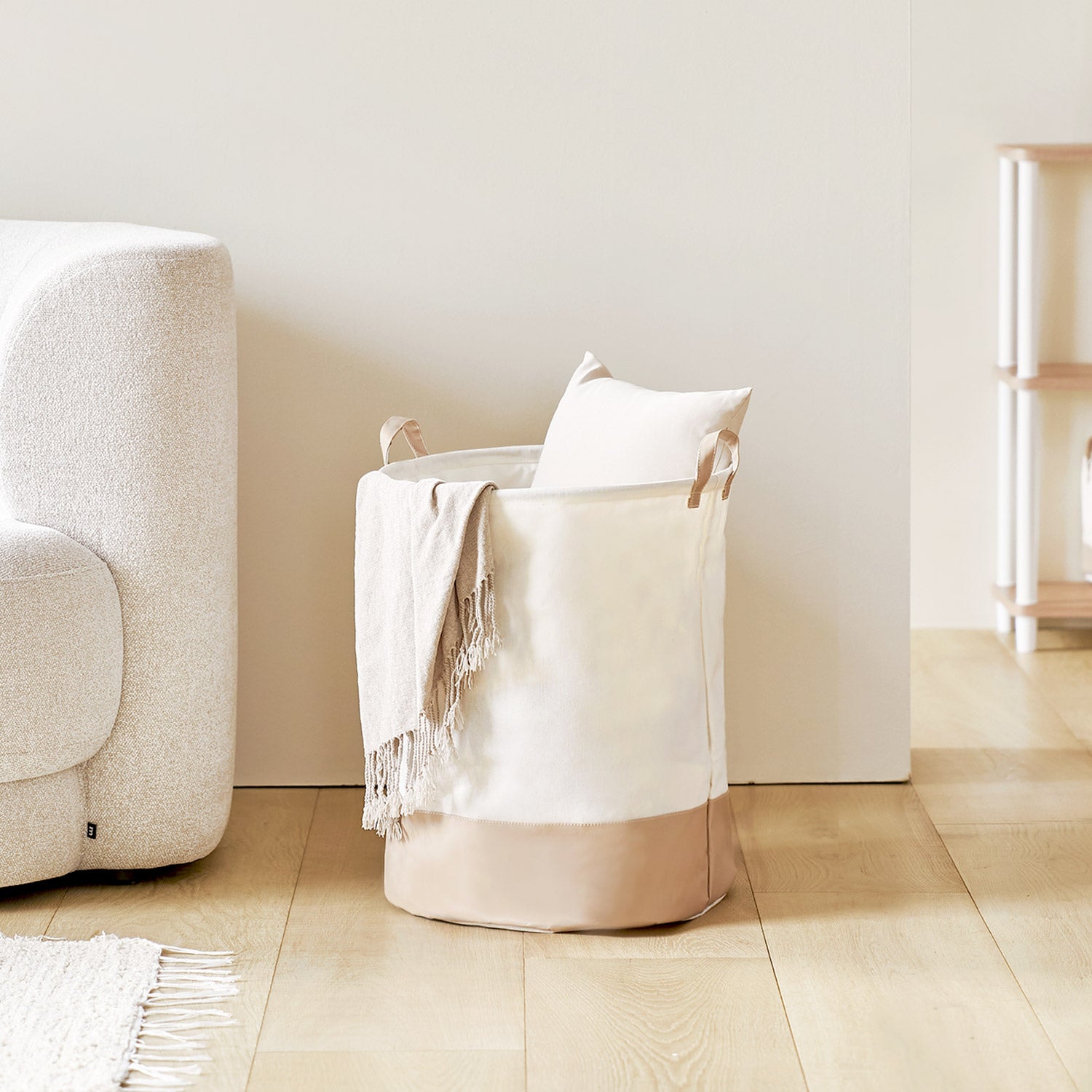 ソファ横に置いてある巾着ラウンドバスケットベージュの中にタオル等小物が入っている様子