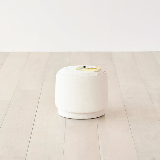 ホワイトの丸みのあるフォルムの収納スツールの上に本とハンドクリームが置かれてある様子