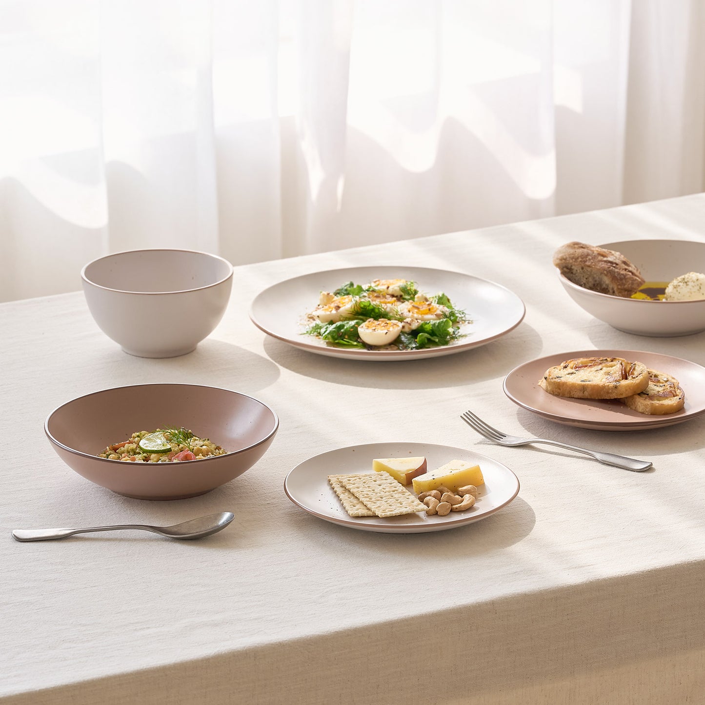 白とピンクのボウルとプレートに料理が乗った食卓