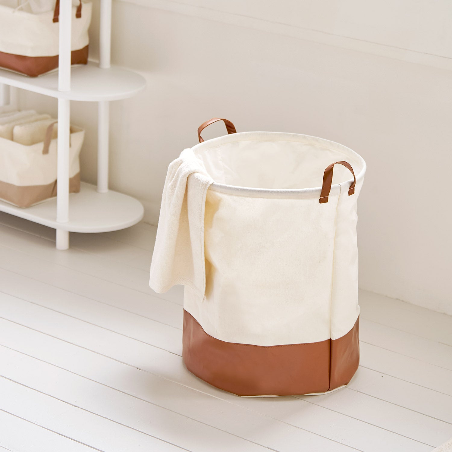 シェルフ横に置いてある巾着ラウンドバスケットブラウンの中にタオル等小物が入っている様子