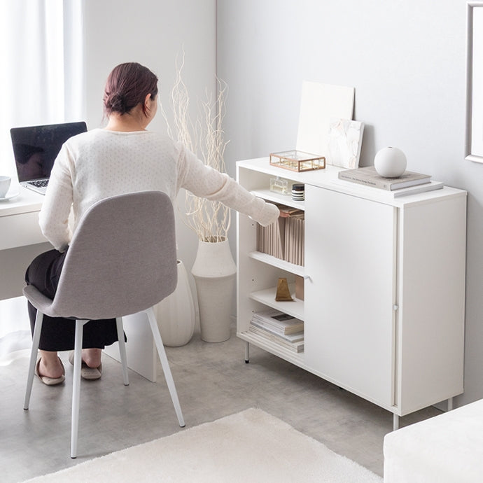 デスクに座った人が扉がスライド式の棚に手を伸ばしている