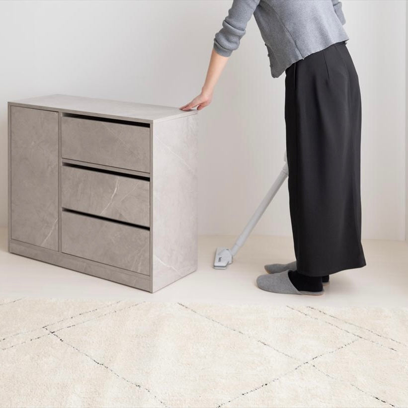 キャスターがついたグレーのチェストを動かしている