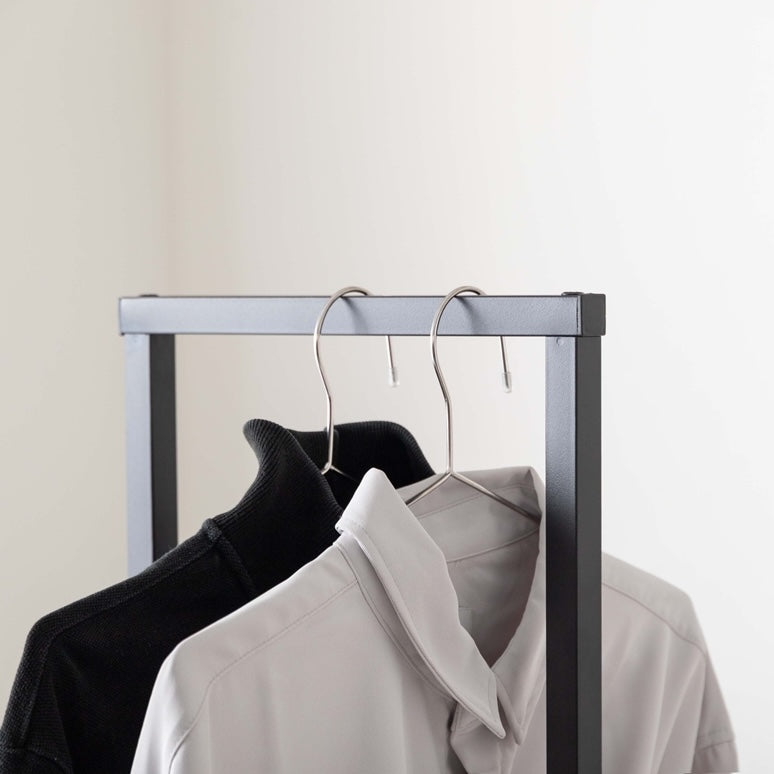 シンプルなブラックのスチール素材のハンガーラックに洋服やカバンがかけられている様子