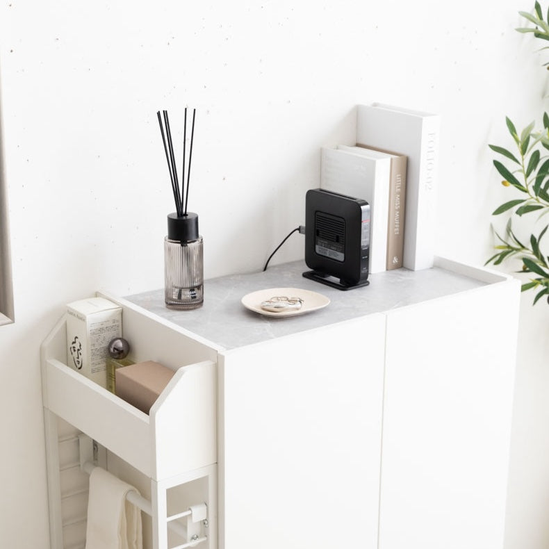ホワイトのラック付きキャビネットに本やディフューザー、アクセサリー、ルーターが置かれている様子