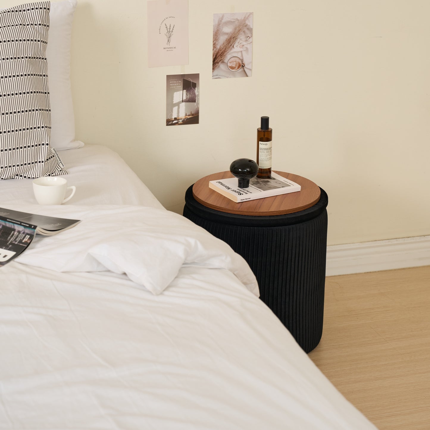 ブラックの楕円型のプリーツ収納がサイドテーブルとしてベッド横に置かれている様子