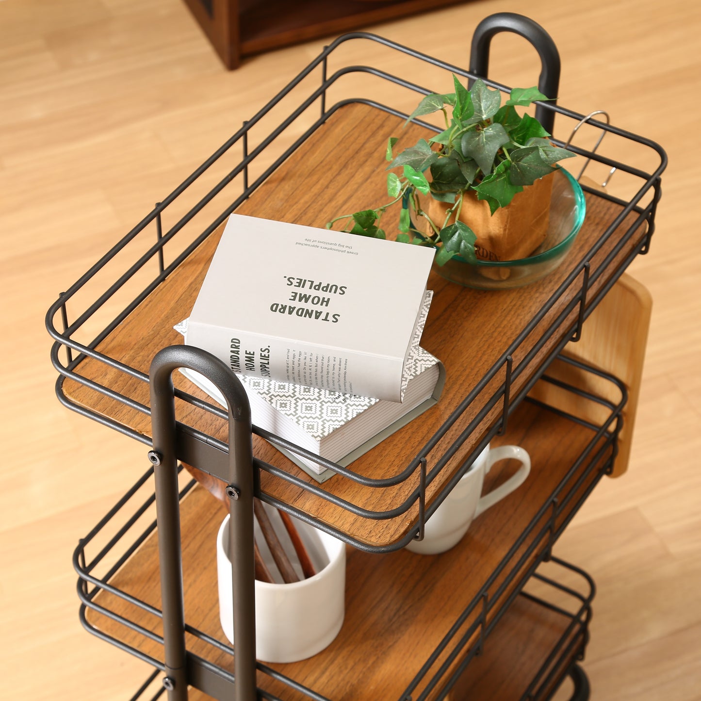 ウッド天板でブラックフレームのワゴンに植物や本、食器などを置いている様子