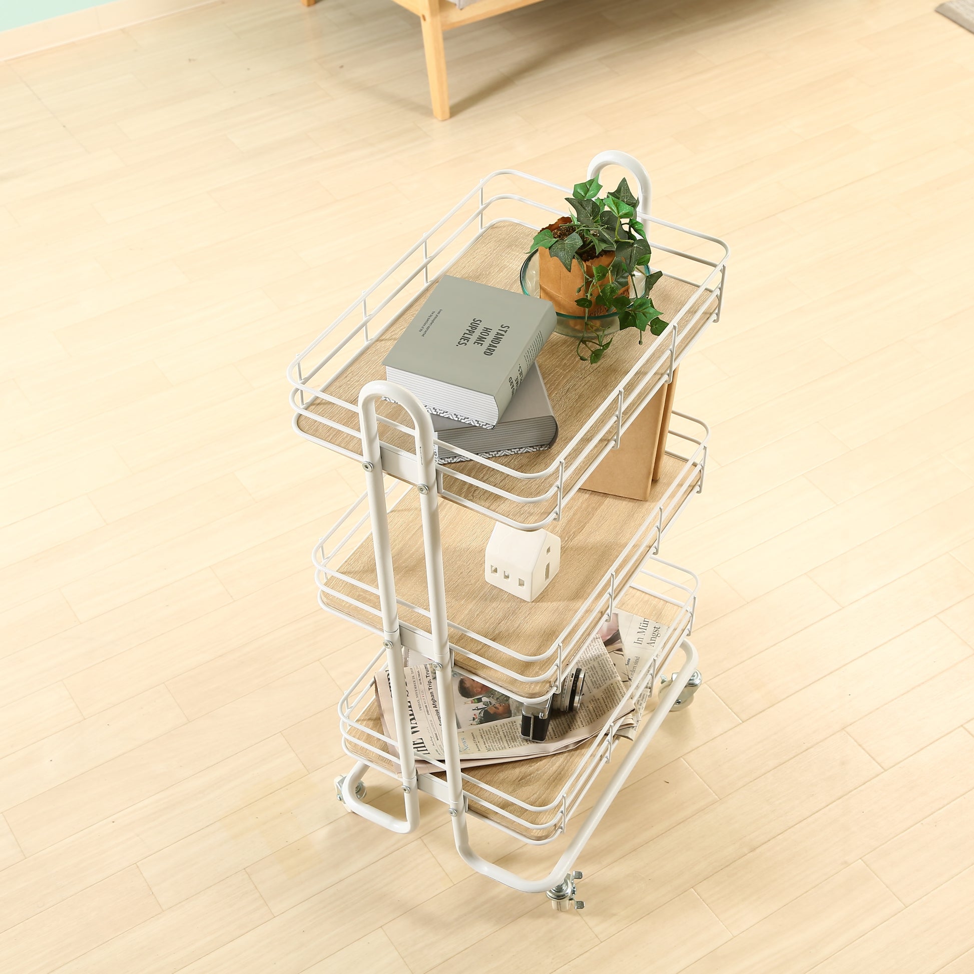 ウッド天板でホワイトフレームのワゴンに植物や本、新聞などが置かれてある様子