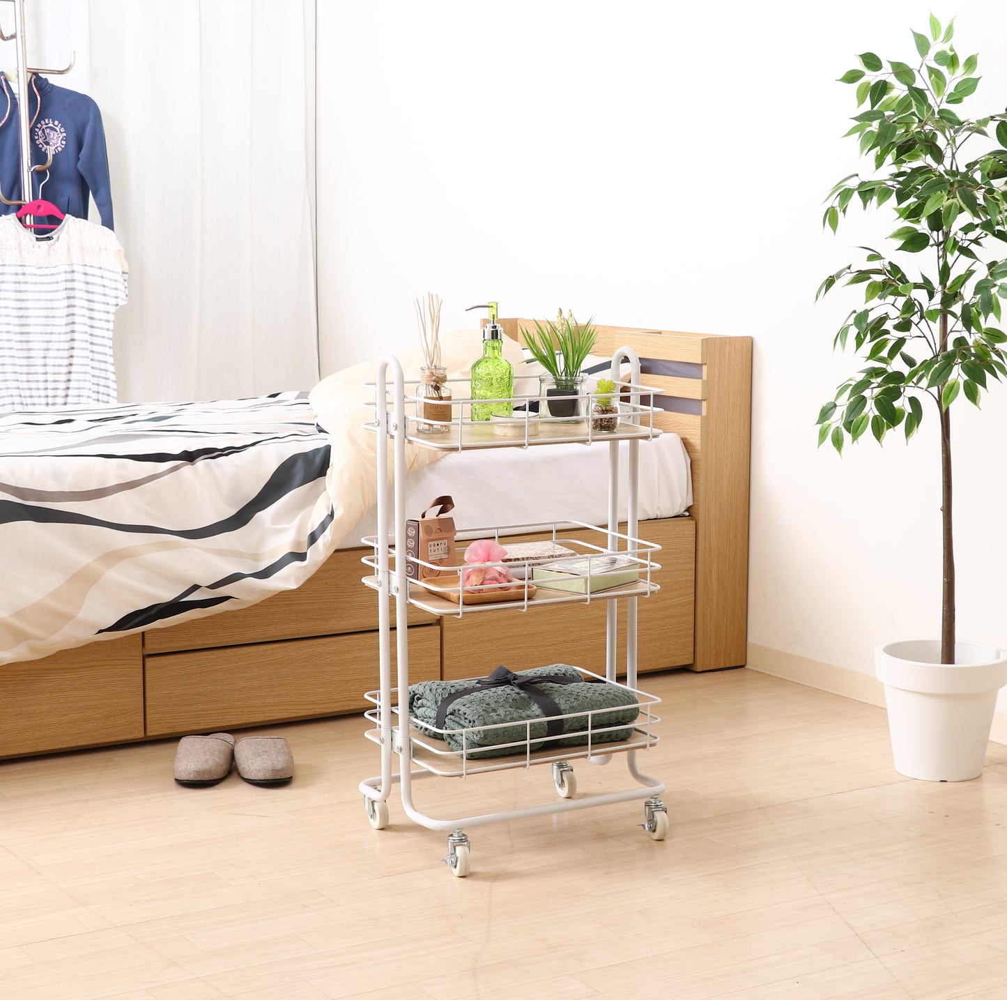 ウッド天板でホワイトフレームのワゴンをベッドのそばに置いている様子