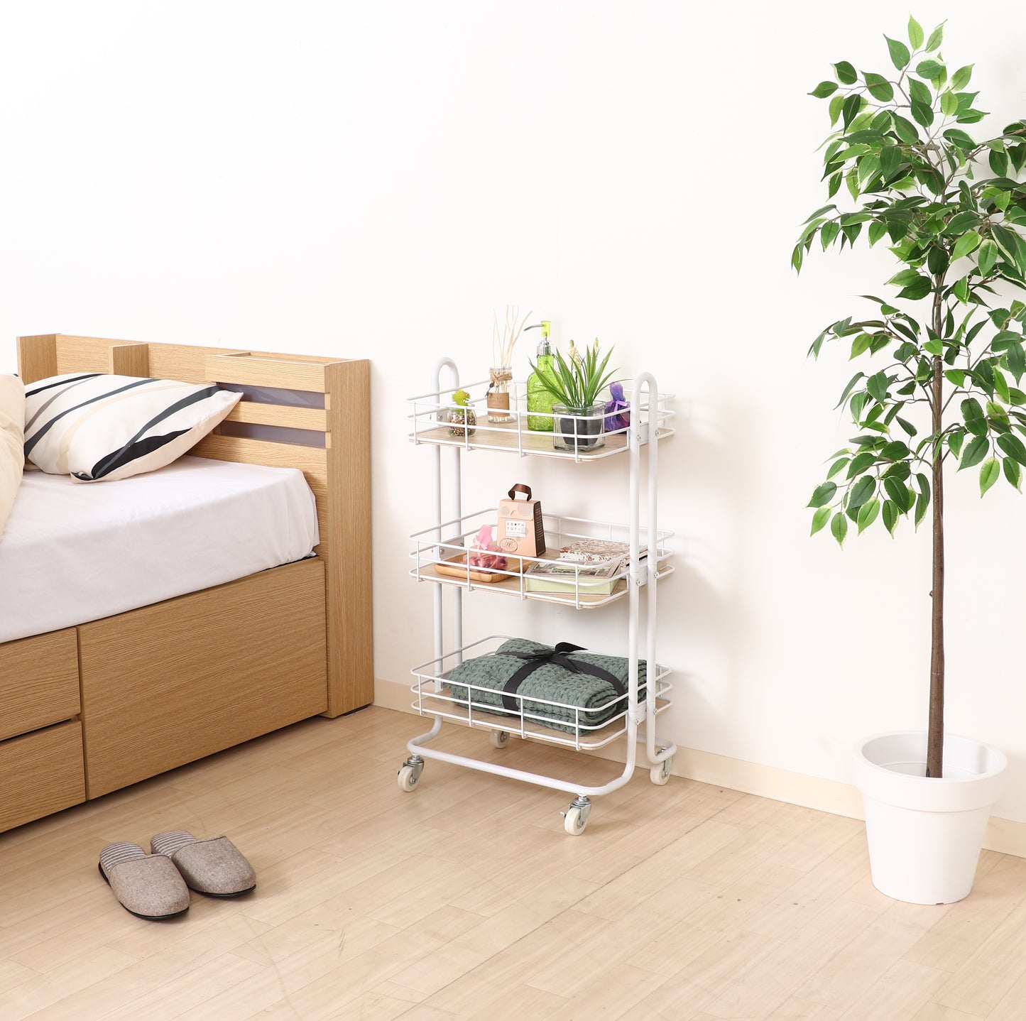 ウッド天板でホワイトフレームのワゴンをベッド横に置いている様子