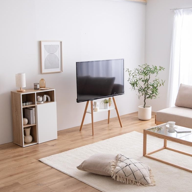 ホワイトのラックが付いたウッド脚のテレビスタンドがリビングに置かれている様子