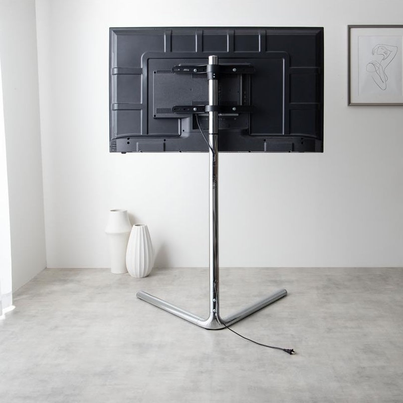 シルバーポールのテレビスタンドのポールにテレビのコードを隠している様子