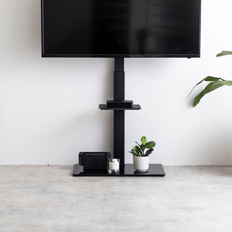 ラック付きのブラックのテレビスタンドが壁に寄せられている様子