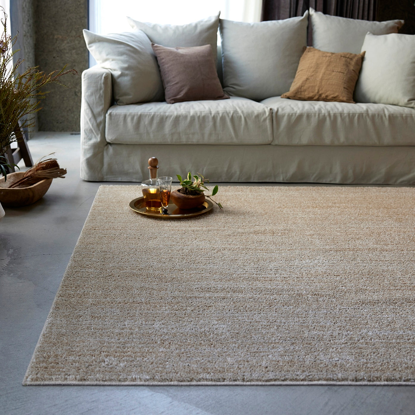 ベージュのナチュラルラグをソファ前に敷いている様子