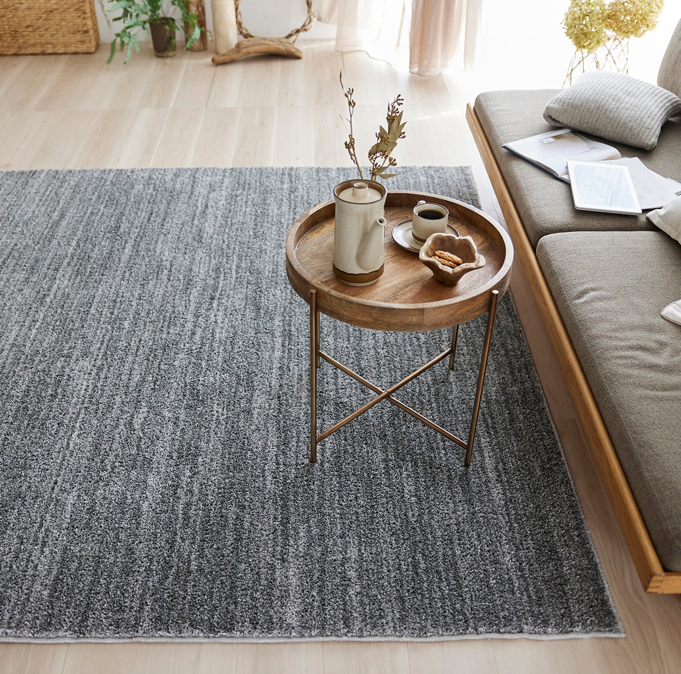 グレーのナチュラルラグをソファ前に敷いている様子