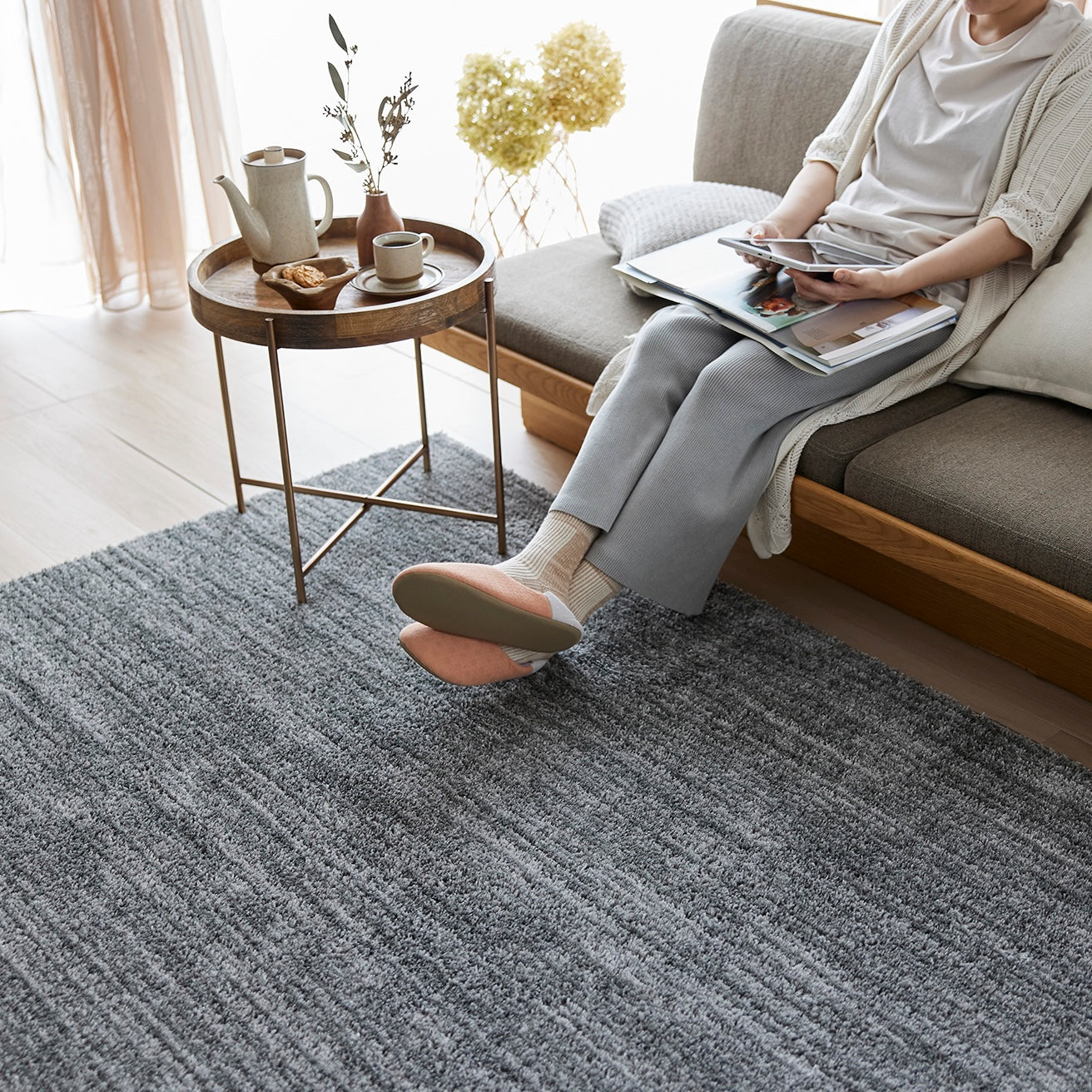 グレーのナチュラルラグをソファ前に敷いている様子