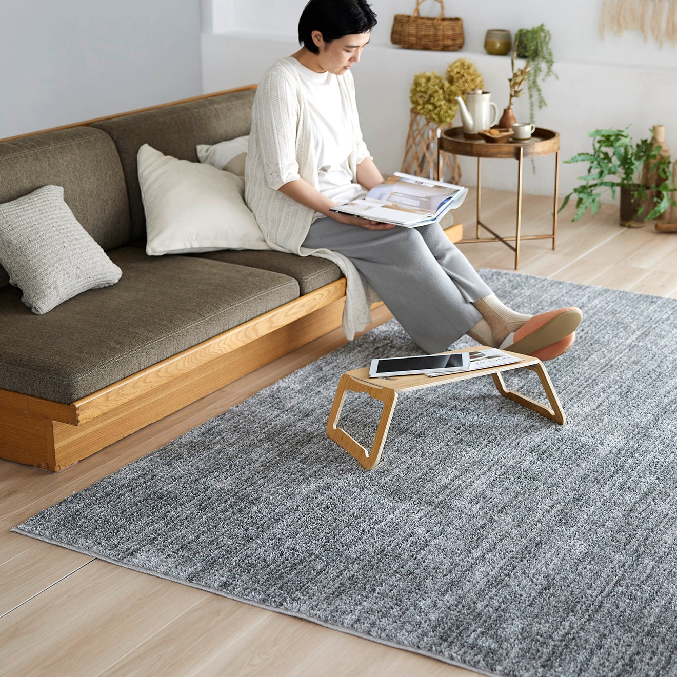 グレーのナチュラルラグをソファ前に敷いている様子