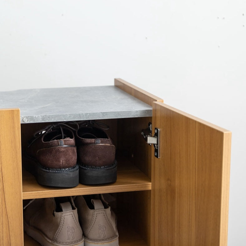 ブラウンのラック付きキャビネットの中に靴を収納している様子