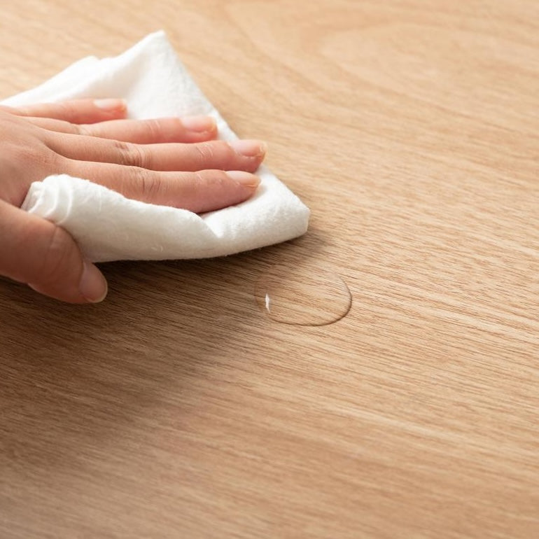 ゴミ箱とキッチンボードが一体となった収納家具の天板にこぼれた水滴を拭いている