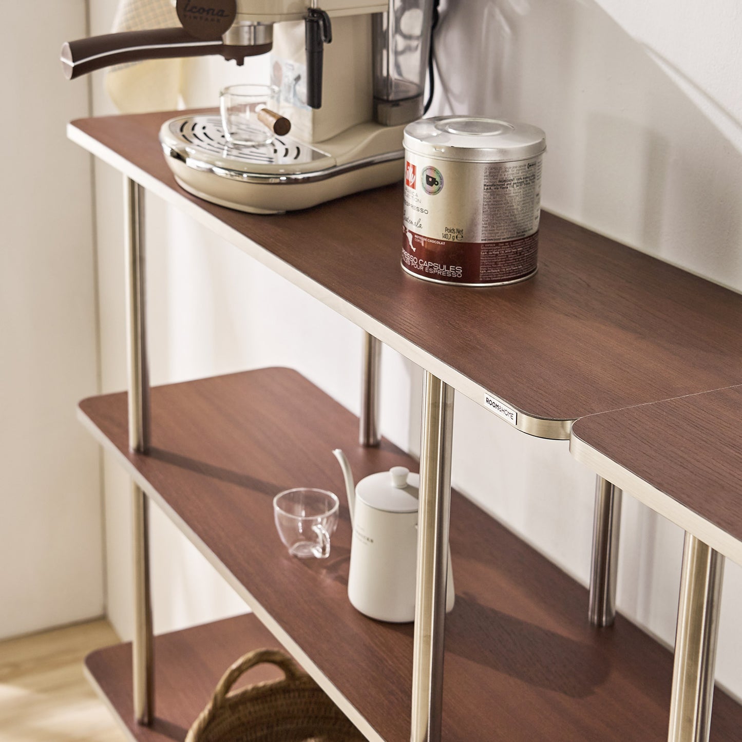 ブラウンのオープンシェルフにコーヒーメーカーやポットとコップなどが置かれてある様子