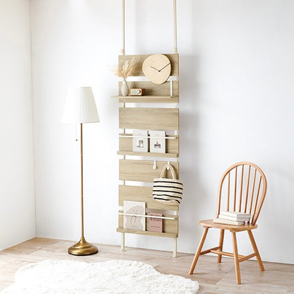 ナチュラルの突っ張りディスプレイラックをフロアライトの横に設置している様子