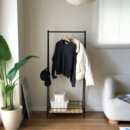 ブラックのスチール製のハンガーラックに洋服や帽子が掛けられている様子