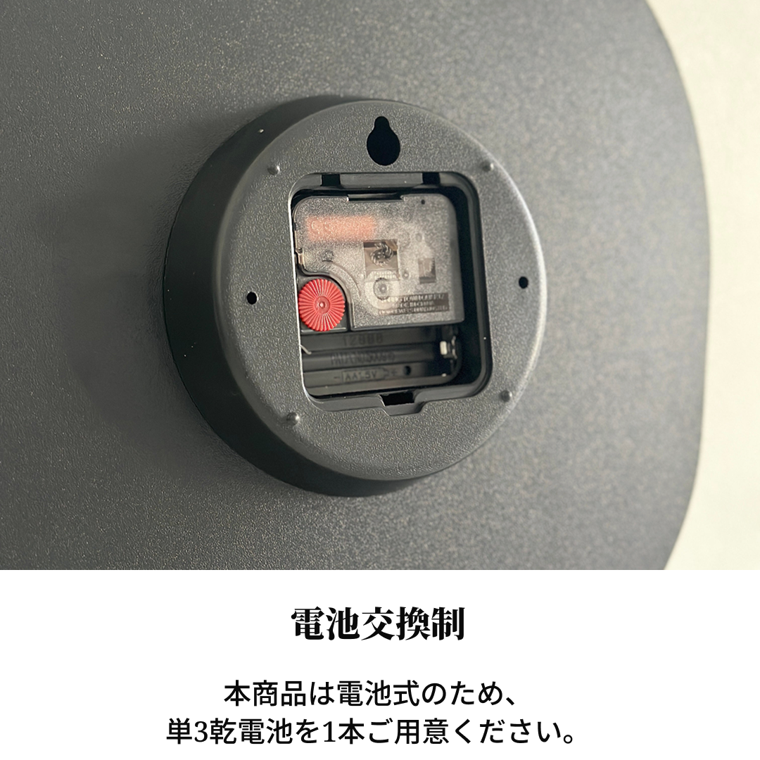 モノクロ掛け時計の黒い円形裏面、内部バッテリー収納と赤いギア機構が見える画像