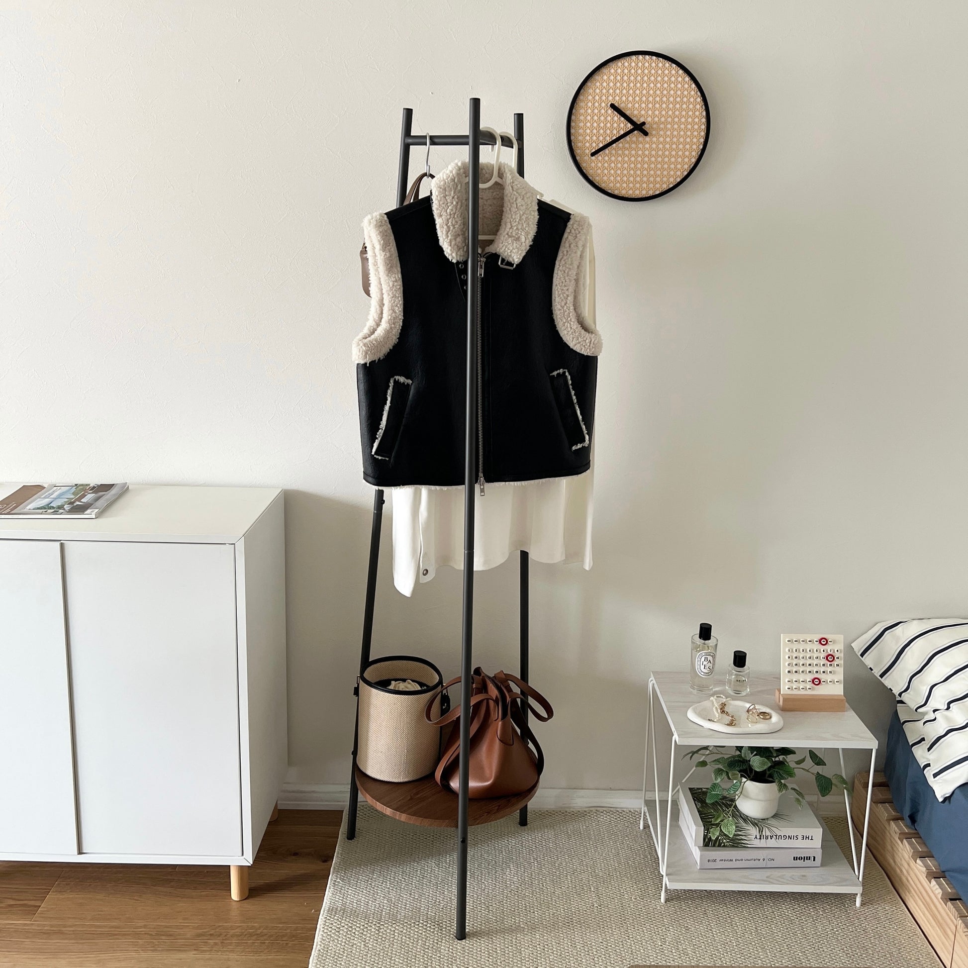 部屋の中で黒いコンパクトでスタイリッシュなハンガーラックに洋服がかかっている様子