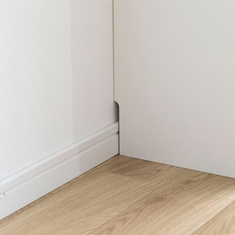 白の扉付きの収納とオープン棚が組み合わさったキャビネットの背面には巾木よけがあることがわかる写真