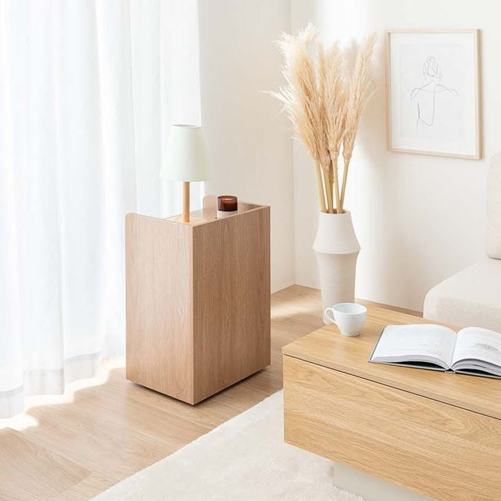 ナチュラルウッドカラーの4つの収納スペースが付いたサイドテーブルにもなる収納ワゴンを回転させて、収納部分が見えないようにスマートに置いている