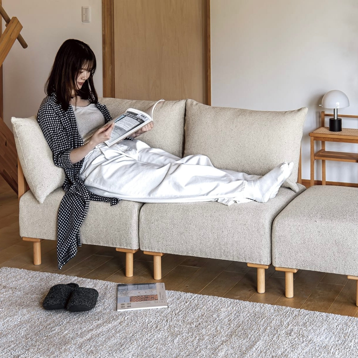 木製フレームのベージュのソファに人が座っている様子