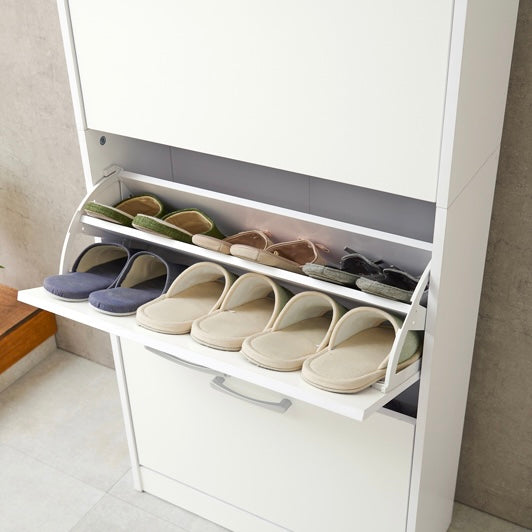 ホワイトのフラップ扉式のシューズケースにスリッパを入れている様子