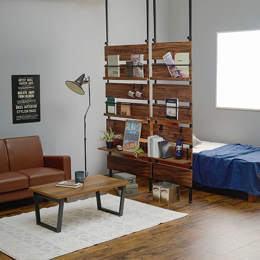 ブラウンの突っ張りディスプレイラックを2つ並べて、部屋の間切りとして設置している様子