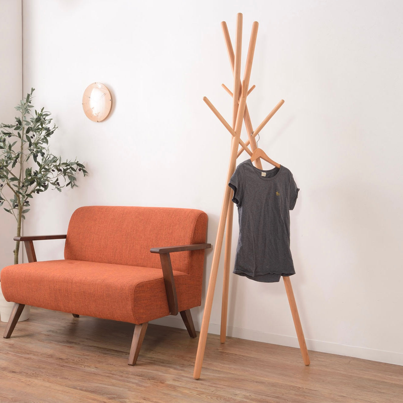 木の枝が交差したようなデザインのハンガーラックがリビングに置かれている様子