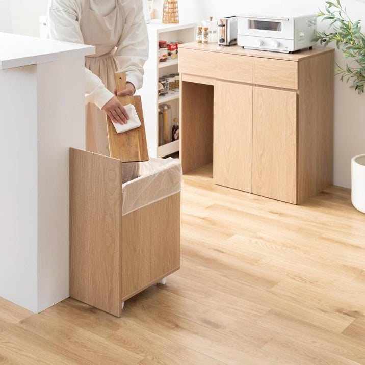 ゴミ箱とキッチンボードが一体となった収納家具を置いているキッチンでゴミ箱を引き出してゴミを捨てている様子