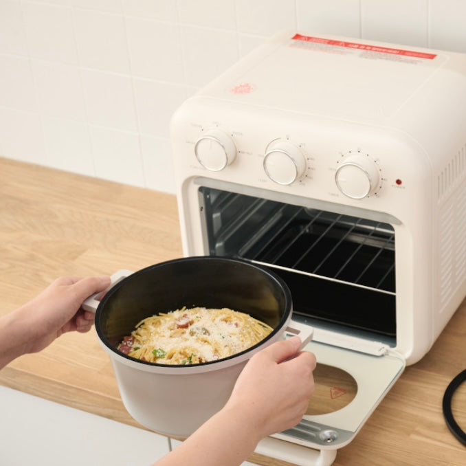 蓋付きの両手鍋をオーブンの中に入れようとしている