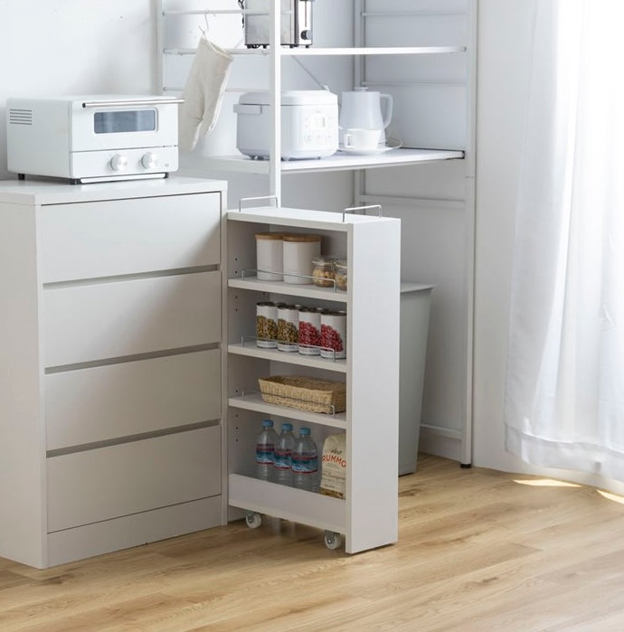 隙間に収まる白の収納ワゴンをキッチンで使い、食品や水のストックを保管している