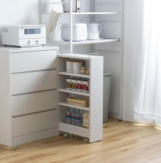 隙間に収まる白の収納ワゴンをキッチンで使い、食品や水のストックを保管している