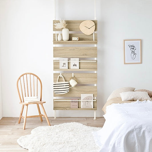 ナチュラルの突っ張りディスプレイラックをベッド横に設置している様子